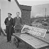 Booking clerk P. J. Scott and other standing next to sign for Cahirciveen, Cahirciveen, Co. Kerry.